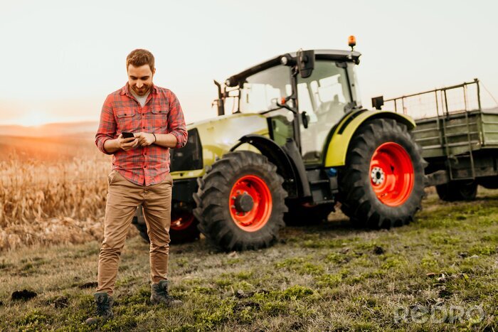 Papier peint  Agriculteur travaillant sur le terrain à l'aide de smartphone dans l'agriculture moderne - fond de tracteur