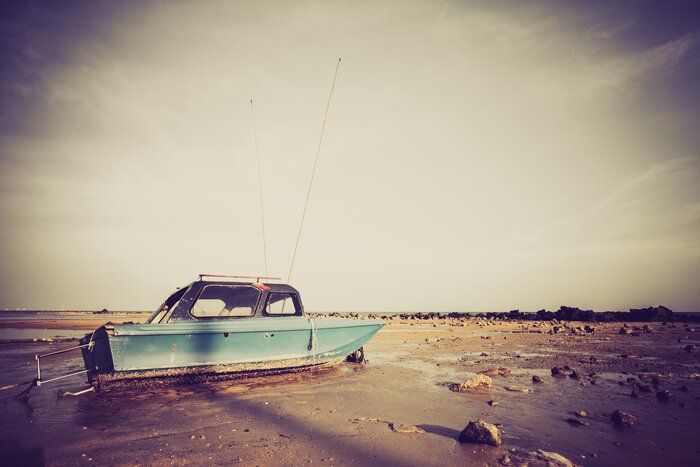 Papier peint  Bateau de pêche sur le sable avec un ciel bleu dans le style rétro