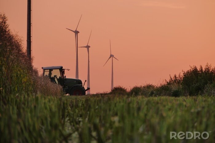 Papier peint  Beautiful shot of a tractor working in the fields with wind power plants in the background