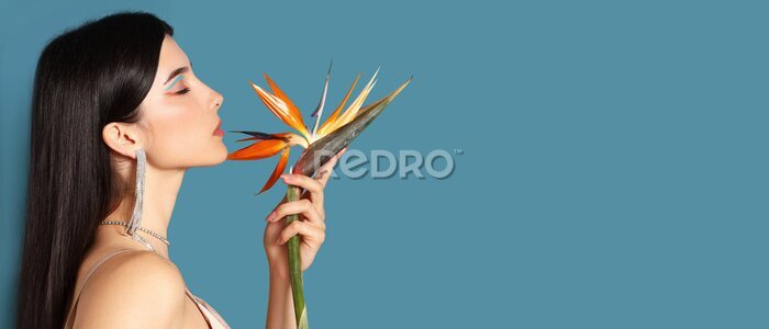 Papier peint  Beautiful young woman holding strelitzia flower on blue background with space for text