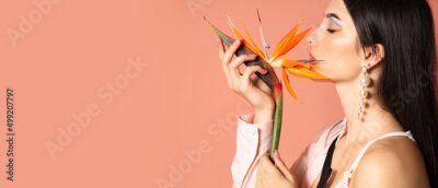 Papier peint  Beautiful young woman holding strelitzia flower on color background with space for text