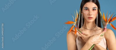Papier peint  Beautiful young woman holding strelitzia flowers on blue background with space for text
