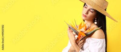 Papier peint  Beautiful young woman holding strelitzia flowers on yellow background with space for text