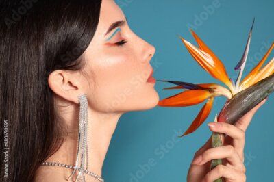 Papier peint  Beautiful young woman with strelitzia flower on color background