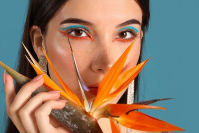 Papier peint  Beautiful young woman with strelitzia flower on color background