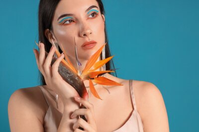 Papier peint  Beautiful young woman with strelitzia flower on color background