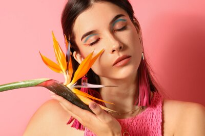 Papier peint  Beautiful young woman with strelitzia flower on color background