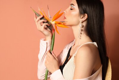 Papier peint  Beautiful young woman with strelitzia flower on color background