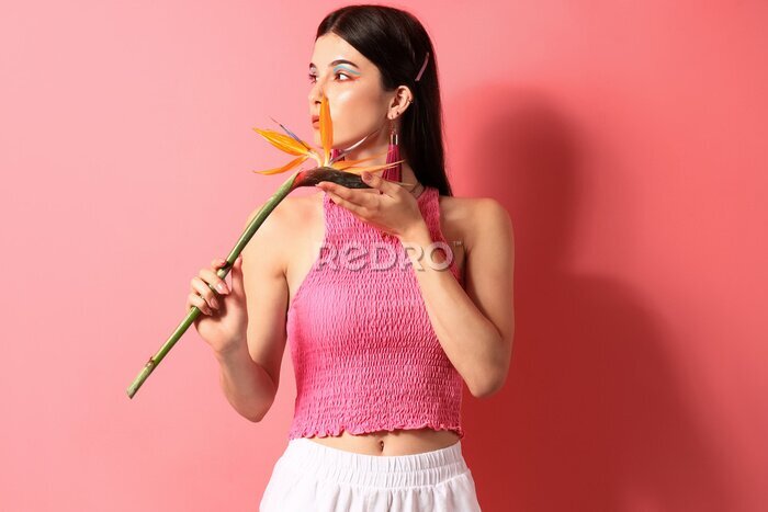 Papier peint  Beautiful young woman with strelitzia flower on color background