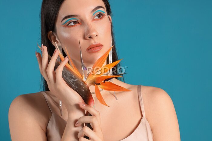 Papier peint  Beautiful young woman with strelitzia flower on color background