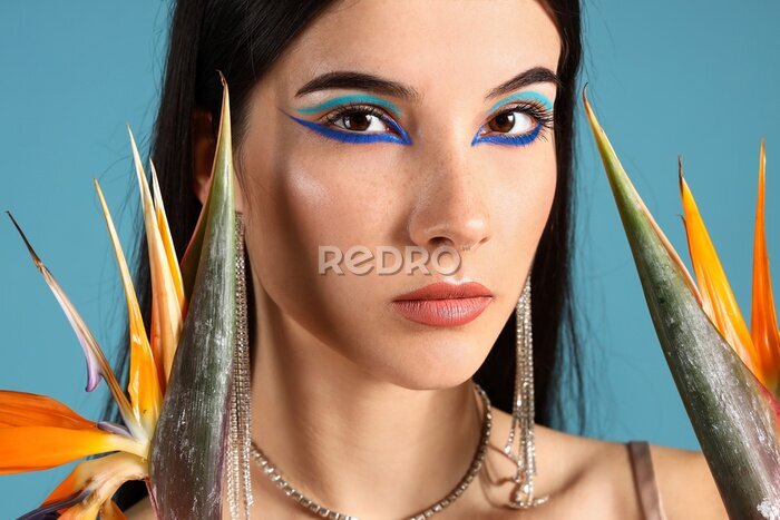Papier peint  Beautiful young woman with strelitzia flowers and bright makeup on blue background
