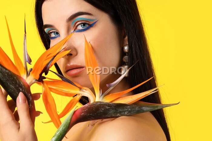 Papier peint  Beautiful young woman with strelitzia flowers and bright makeup on yellow background
