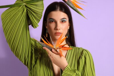 Papier peint  Beautiful young woman with strelitzia flowers on color background