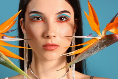 Papier peint  Beautiful young woman with strelitzia flowers on color background