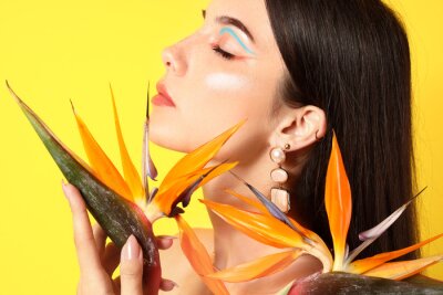 Papier peint  Beautiful young woman with strelitzia flowers on color background