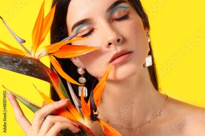 Papier peint  Beautiful young woman with strelitzia flowers on color background