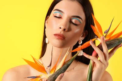 Papier peint  Beautiful young woman with strelitzia flowers on color background