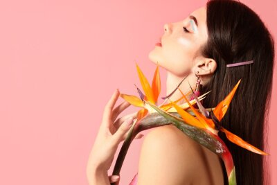 Papier peint  Beautiful young woman with strelitzia flowers on color background