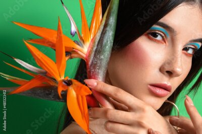 Papier peint  Beautiful young woman with strelitzia flowers on color background
