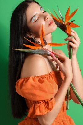 Papier peint  Beautiful young woman with strelitzia flowers on color background