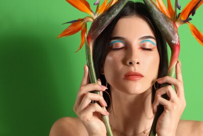Papier peint  Beautiful young woman with strelitzia flowers on color background