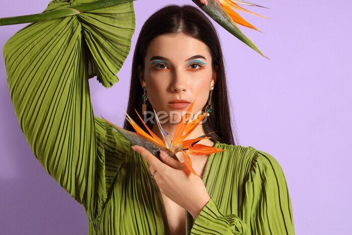 Papier peint  Beautiful young woman with strelitzia flowers on color background
