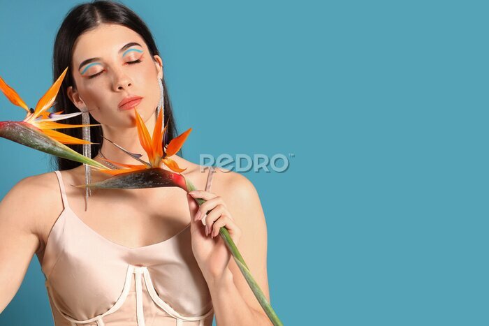 Papier peint  Beautiful young woman with strelitzia flowers on color background
