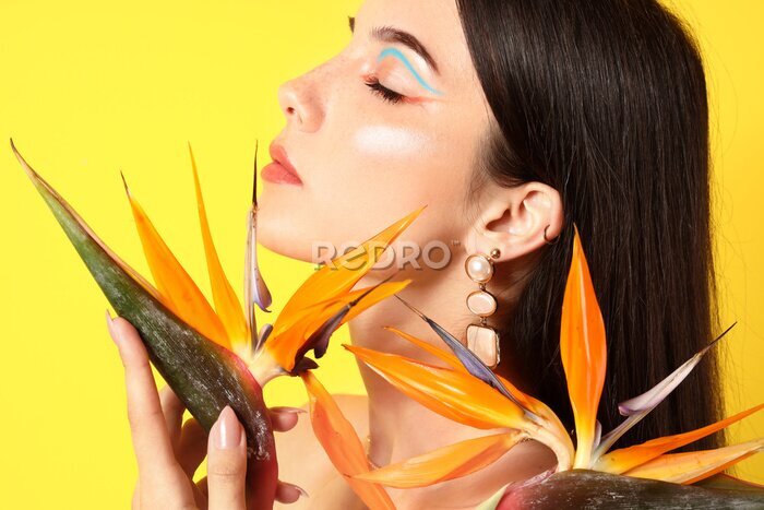 Papier peint  Beautiful young woman with strelitzia flowers on color background