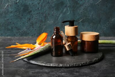Papier peint  Bottles of cosmetic products and beautiful strelitzia flower on dark background