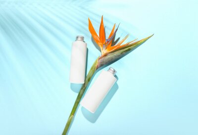 Papier peint  Bottles of cosmetic products and beautiful strelitzia flowers on blue background