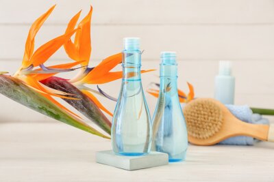 Papier peint  Bottles of cosmetic products and beautiful strelitzia flowers on light wooden background