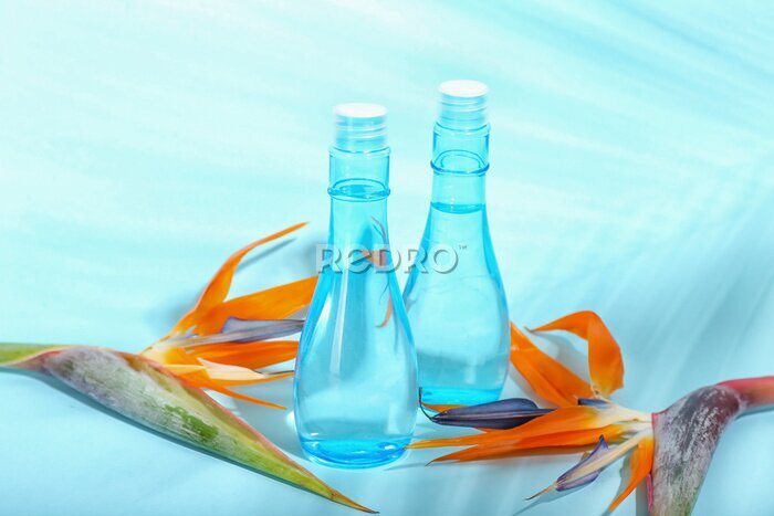 Papier peint  Bottles of cosmetic products and strelitzia flowers on blue background