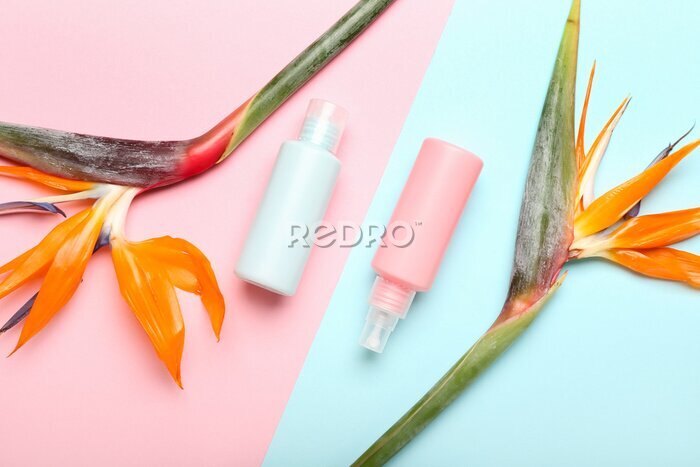 Papier peint  Bottles of cosmetic products and strelitzia flowers on color background