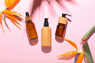 Papier peint  Bottles of cosmetic products and strelitzia flowers on pink background