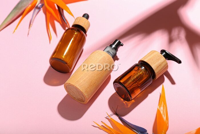Papier peint  Bottles of cosmetic products and strelitzia flowers on pink background