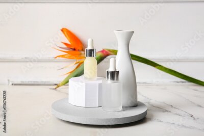 Papier peint  Bottles of cosmetic products with beautiful strelitzia flower, plaster podiums and vase on light background