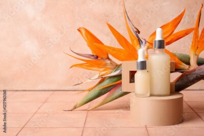 Papier peint  Bottles of cosmetic products with beautiful strelitzia flowers and plaster podiums on beige tile table