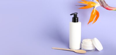 Papier peint  Cosmetic products and strelitzia flower on lilac background with space for text