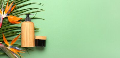 Papier peint  Cosmetic products, tropical leaf and strelitzia flowers on green background with space for text