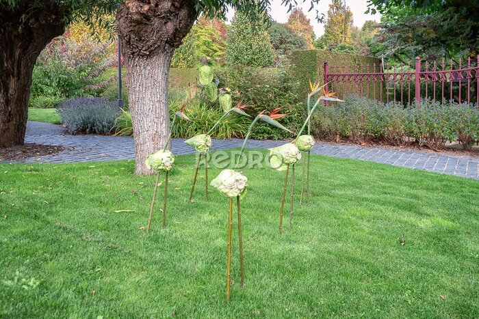 Papier peint  Des échassiers en bâtons, un chou et un Strelitzia reginae en guise de décoration dans le jardin