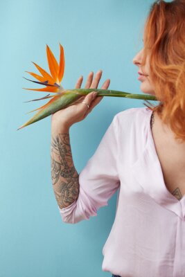 Papier peint  Femme tenant une fleur de strelitzia sur fond bleu