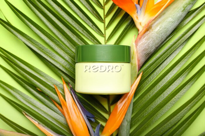 Papier peint  Jar of cosmetic product with palm leaf and strelitzia flowers on green background, closeup
