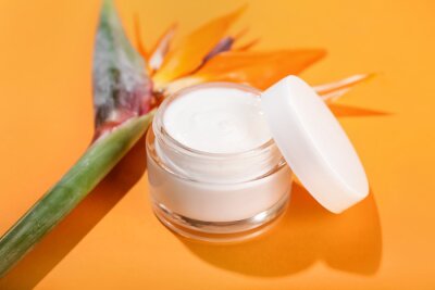 Papier peint  Jar of cream and strelitzia flowers on color background, closeup