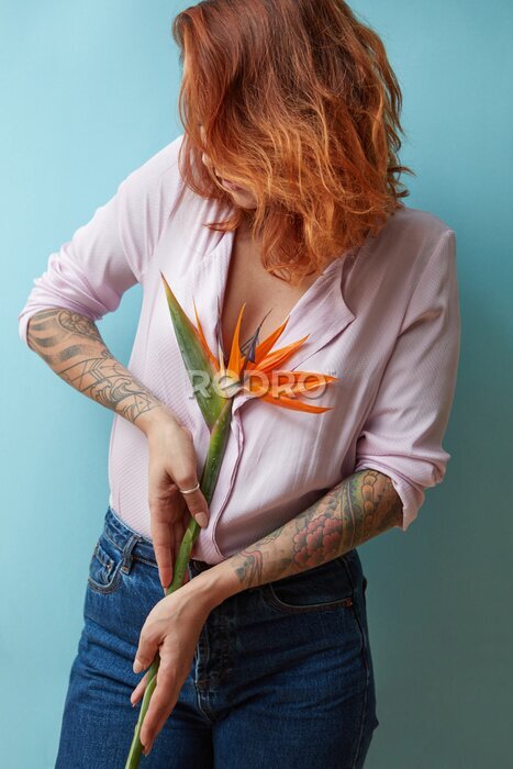 Papier peint  Jeune fille rousse tenant un strelitzia sur fond bleu