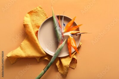 Papier peint  Plate with beautiful strelitzia flower and napkin on orange background