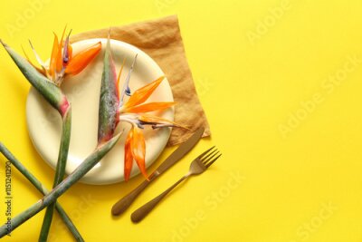 Papier peint  Plate with beautiful strelitzia flowers, cutlery and napkin on yellow background