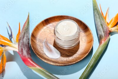 Papier peint  Plate with jar of cream and strelitzia flowers on color background