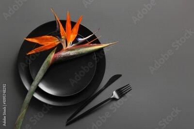 Papier peint  Plates with beautiful strelitzia flower and cutlery on grey background
