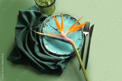 Papier peint  Plates with beautiful strelitzia flower, cutlery and napkin on green background
