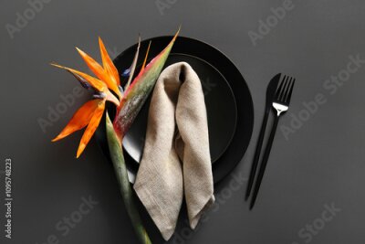 Papier peint  Plates with beautiful strelitzia flower, cutlery and napkin on grey background